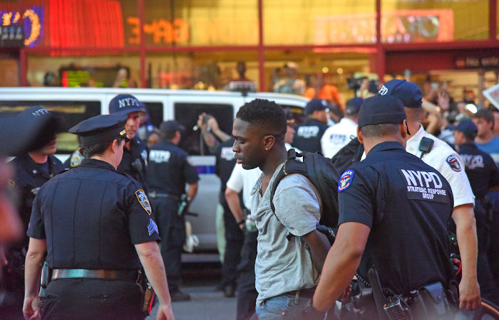 Polícia abordando um jovem negro em referência à consciência negra.